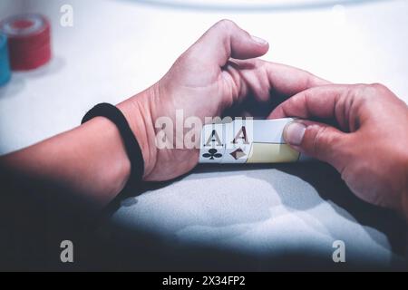 Nahaufnahme eines Pokerspielers, der heimlich ein Paar Asse hält, die stärkste Starthand in Texas Holdem Stockfoto