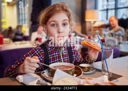 Mädchen isst den ersten Gang am Tisch im Café. Stockfoto