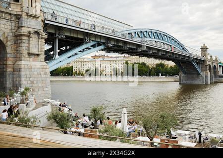 MOSKAU, RUSSLAND - 29. Juni 2015: Menschen in einem Freiluft-Café an der Stütze der Puschkinski-Brücke über den Moskauer Fluss. Brücke verbindet Pushkin emba Stockfoto