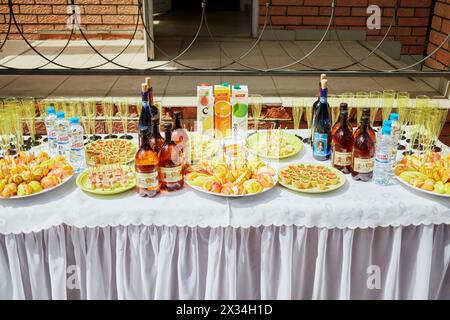 MOSKAU, RUSSLAND - 30. MAI 2015: Feiertagstisch voller Flaschen Wein, Saft, Wasser und Snacks auf Tellern. Stockfoto