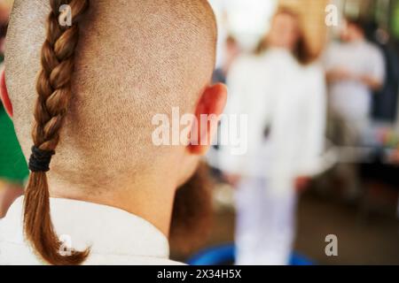 Hinterkopf eines jungen Mannes mit rasiertem Kopf und geflochtenem Zopf. Stockfoto