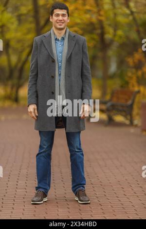 Porträt im vollwertigen jungen Mann im grauen Fell im Herbstpark Stockfoto
