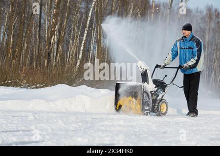 Der Mensch entfernt Schnee mit einer Gasschneewerfer am Wintertag. Stockfoto