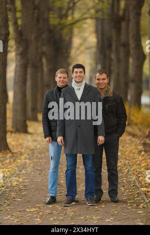 Vollständiges Porträt von drei Freunden in der Gasse im Herbstpark, lächelnd Stockfoto