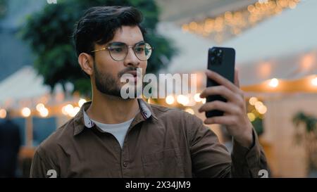 Gutaussehender erfolgreicher indischer arabischer ethnischer Mann männlicher Student Gen z Guy Geschäftsmann Vlogger Influencer sprechen Aufzeichnung Online-Videoanruf mit Gadget Stockfoto