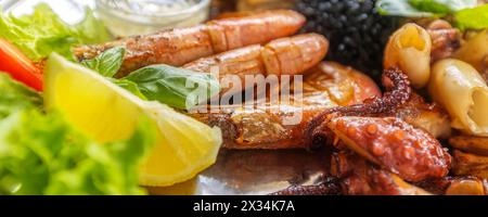 Gerösteter gemischter Fisch und Meeresfrüchte-Teller mit Calamari-Tintenfischen, Garnelen und gegrilltem Oktopusbanner, mediterrane Speisen Stockfoto