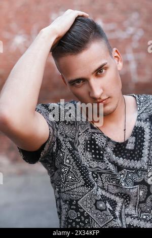 Nahaufnahme Porträt Eines jungen Hipsters in Einem schwarzen Vintage-T-Shirt auf Einem Hintergrund aus roten Ziegeln. Stockfoto