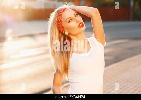 Porträt Eines hübschen Hipster-Mädchens mit roten Lippen in weißem T-Shirt auf der Straße bei Sonnenuntergang Stockfoto