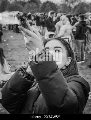 Schwarz-weiß-Bild einer Frau, die während der Veranstaltung 420 in London einen großen CannabisJoint raucht. Stockfoto