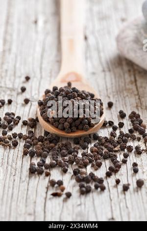 Holzlöffel mit Pfeffer auf rustikalem Vorder- und Hintergrund Stockfoto