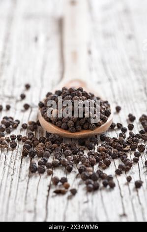 Holzlöffel mit Pfeffer auf rustikalem Vorder- und Hintergrund Stockfoto