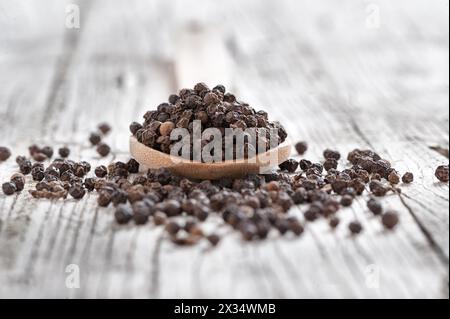 Holzlöffel mit Pfeffer auf rustikalem Vorder- und Hintergrund Stockfoto