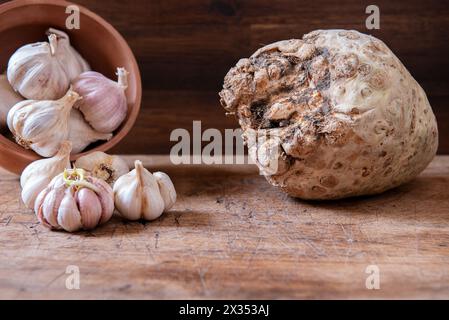 Bio-Knoblauch im Topf und frische Selleriewurzel auf rustikalem Holztisch. Hintergrund zu Lebensmitteln. Stockfoto