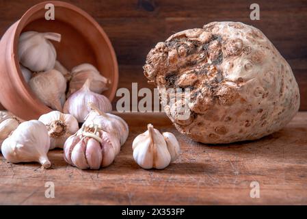 Bio-Knoblauch im Topf und frische Selleriewurzel auf rustikalem Holztisch. Hintergrund zu Lebensmitteln. Stockfoto