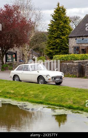 1967 Oldtimer MG B GT parkt am Dorfteich im Dorf Hartington, England, Großbritannien Stockfoto