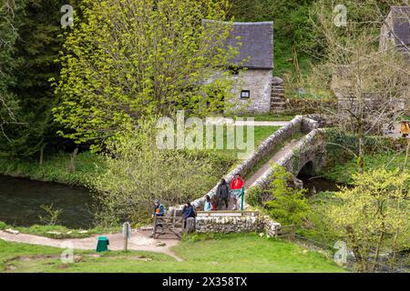 Wanderer und Wanderer überqueren VIATORS BRÜCKE über den Fluss Dove bei Milldale im English Peak District, der durch izaak Walton berühmt wurde Stockfoto