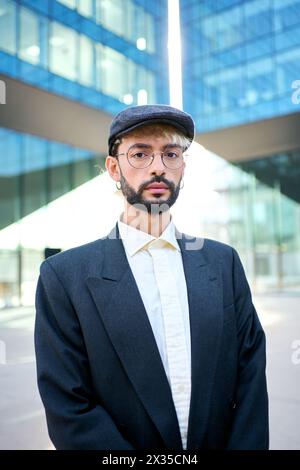 Ein junger kaukasischer Hipster-Mann in einem eleganten blauen Anzug, Hut und Brille, der ernst und selbstbewusst steht Stockfoto