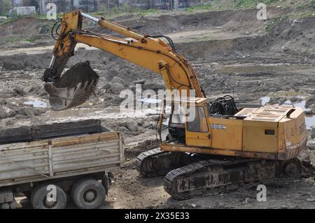 Der Bagger lädt ausgehobenen Boden in einen großen Lkw in einem bewohnten Gebiet Stockfoto