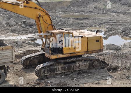 Der Bagger lädt ausgehobenen Boden in einen großen Lkw in einem bewohnten Gebiet Stockfoto