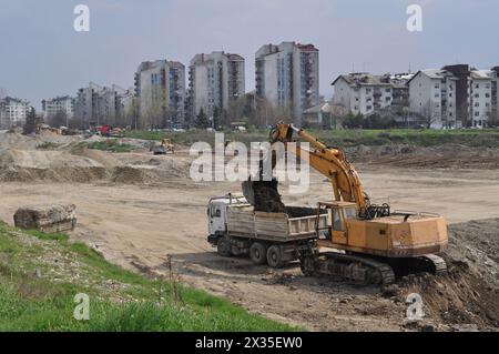 Der Bagger lädt ausgehobenen Boden in einen großen Lkw in einem bewohnten Gebiet Stockfoto