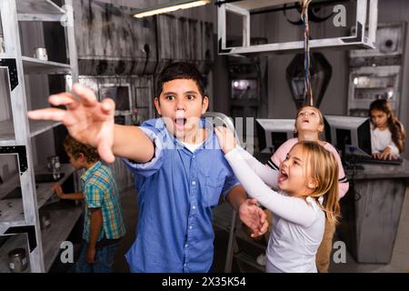 Kleines Mädchen brüllt Jungen an, der im Bunker des Quest-Zimmers nach etwas greift Stockfoto