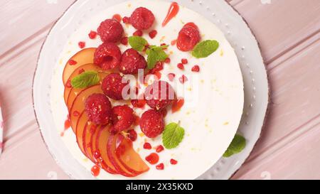 Käsekuchen mit frischen Himbeeren, Pflaumen und Minzblättern. Stockfoto