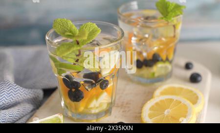 Sommerliche gesunde Cocktails aus Zitruswasser, Limonaden oder Mojitos, mit Limone Zitronenorange Blaubeeren und Minze, Diät Entgiftungsgetränke, in Gläsern Stockfoto