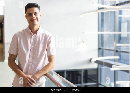 Ein junger, birassischer Mann, der in einem modernen Geschäftsbüro gelandet ist, ein rosa Hemd trägt, mit Kopie Stockfoto