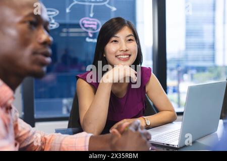 Afroamerikaner und asiatische Frau arbeiten freudig in einem modernen Büro zusammen Stockfoto