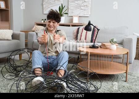 Ein junger Mann mit Verbrennungsgesicht und Drähten, der zu Hause sitzt Stockfoto