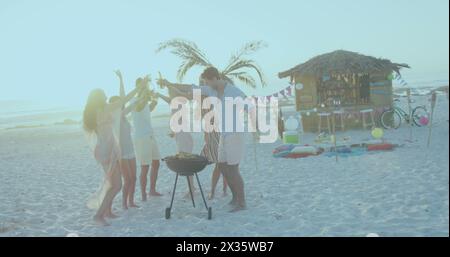Eine Gruppe von Freunden genießt ein Barbecue am Strand bei Sonnenuntergang Stockfoto