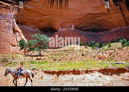 Mädchen auf Cowboypferd, Mummy Cave Ruin, Canyon de Chelly National Monument, Gebiet der Navajo Nation im Nordosten des US-Bundesstaates Arizona. Stockfoto