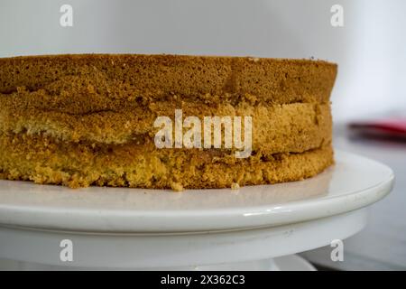 Ein Stück Kuchen mit einem weißen Teller darunter. Der Kuchen ist braun und hat eine bröckelige Textur Stockfoto