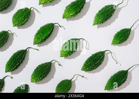 Frische grüne Bittermelonen auf weißem Hintergrund. Kreativszene für Werbung und Branding für Kosmetik oder Produkte mit Inhaltsstoffen von Bit Stockfoto