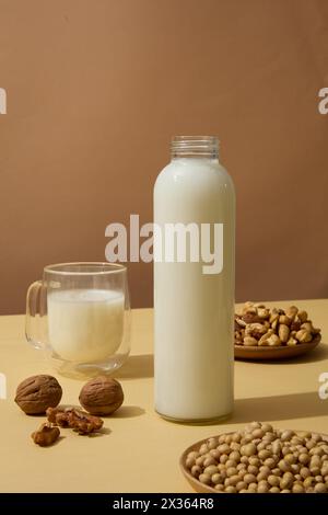 Holzgerichte aus Sojabohnen, Cashewnüssen und Walnüssen auf beigefarbener Oberfläche mit Milchbehältern. Nüsse sind eine große Quelle für mehrere Nährstoffe, ich Stockfoto