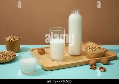 Leere Etikettenflasche und ein mit Bio-Milch gefülltes Glas auf Holztablett. Nur wenige Walnüsse. Sojabohnen sind ein besonderes Frühstück für viele Kulte Stockfoto