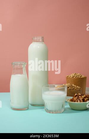 Der rosafarbene Hintergrund enthielt zwei Flaschen ohne Marke und einen mit Milch gefüllten Becher. Einige Schüsseln mit Walnüssen und Sojabohnen wurden ausgestellt. Branding-Mockup mit leerem Labor Stockfoto