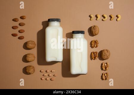 Vor braunem Hintergrund, zwei Milchflaschen mit leerem Etikett und einige verschiedene Arten von Nüssen. Blick von oben. Nüsse und Bohnen sind essentiell für die allgemeine Heilung Stockfoto