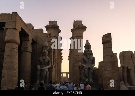 Luxor, Ägypten - 25. November 2023: Touristen besuchen den berühmten Luxor Tempel in Ägypten mit den Ramesses II Statuen bei Sonnenuntergang Stockfoto