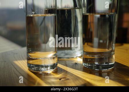 Zwei Gläser stilles Wasser und eine Flasche auf dem Tisch, Kontralichtaufnahme im Innenbereich Stockfoto