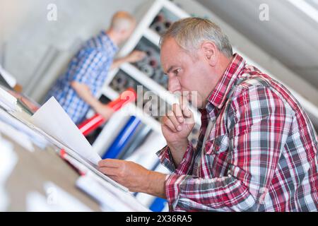 Arbeiter mittleren Alters, der Papierkram tief in Konzentration liest Stockfoto