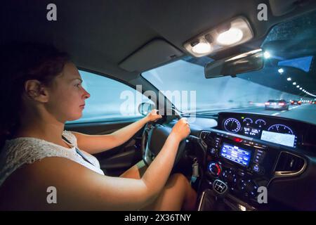 Frau fährt Auto im beleuchteten Tunnel. Stockfoto