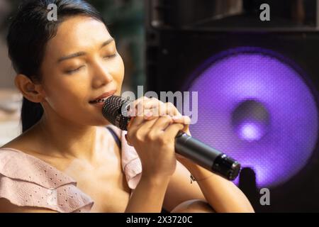 Die junge Frau singt mit Emotionen ins Mikrofon Stockfoto