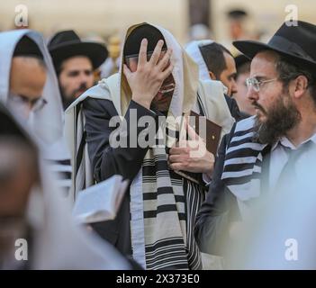 Jerusalem, Israel. April 2024. Ein jüdischer Mann, der mit einem Tallit bedeckt ist und unter anderem ein Gebetsbuch (Sidur) hält und sehr emotional an der Klagemauer betet, hält seine Hand auf seiner Stirn. Quelle: Yoram Biberman/Alamy Live News. Stockfoto