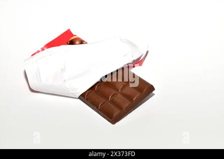 Ein Schokoladenriegel in einer Papierverpackung liegt auf weißem Hintergrund. Stockfoto