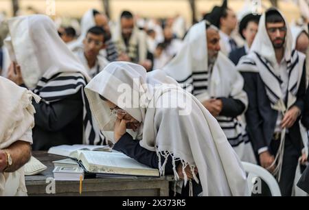 Jerusalem, Israel. April 2024. Ein jüdischer Mann, der mit einem Tallit bedeckt ist, steht unter anderem und betet aus einem Gebetsbuch bei The Wailing Wall Credit: Yoram Biberman/Alamy Live News. Stockfoto