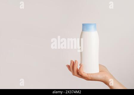 Frau Hand hält weiße Flasche Shampoo oder Haarspülung auf weißem Hintergrund, Kopierraum Stockfoto