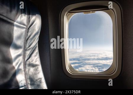 Eine leere Leder Stuhl im Flugzeug. Blau Sitz neben Fenster mit blauen Himmel in fliegenden Flugzeug. Stockfoto