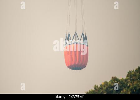 bambi-Eimer mit Wasser für die Luftlöschbekämpfung wird von Ketten über Bäumen hochgezogen Konzept Feuerwehr Notfallrettung Ausrüstung für Ersthelfer Stockfoto