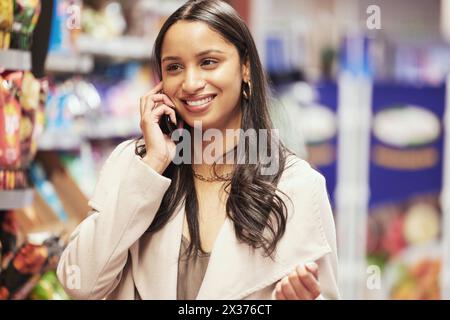 Glückliches, Frauen- und Lebensmitteleinkauf mit Smartphone zur Kommunikation der Checkliste im Supermarkt. Weibliche Person, Käuferin und Handy für Gespräche Stockfoto